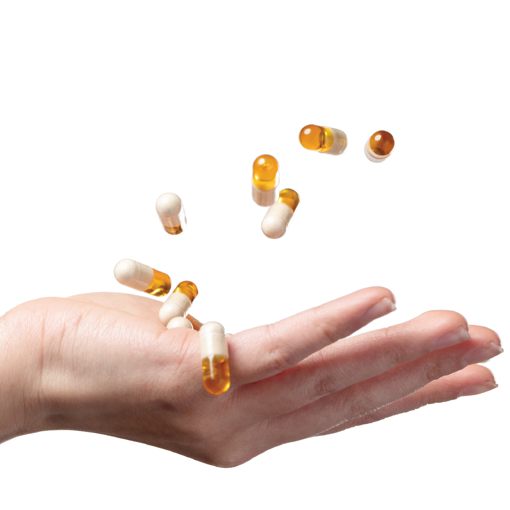 A hand tossing AFTER HOURS yellow and white supplement capsules in the air on a white background.