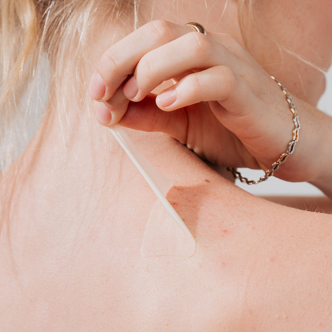 Someone peels a GOO GETTER Body patch off the back of their shoulder near the neck.