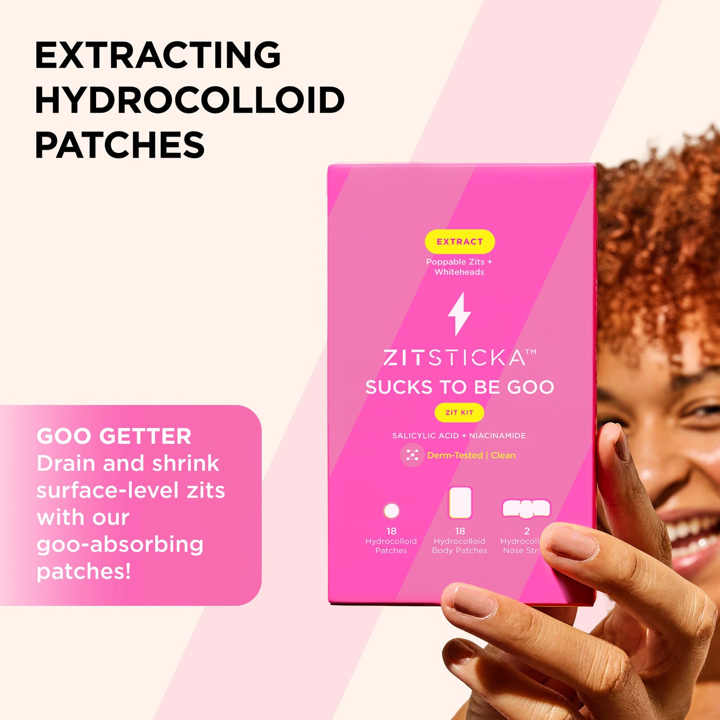 A person holds a pink SUCKS TO BE GOO Kit box, smiling at the camera.