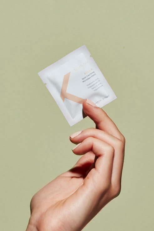 A hand holds a Free Gift: Best Seller Killa Sample sachet against a plain light green background.