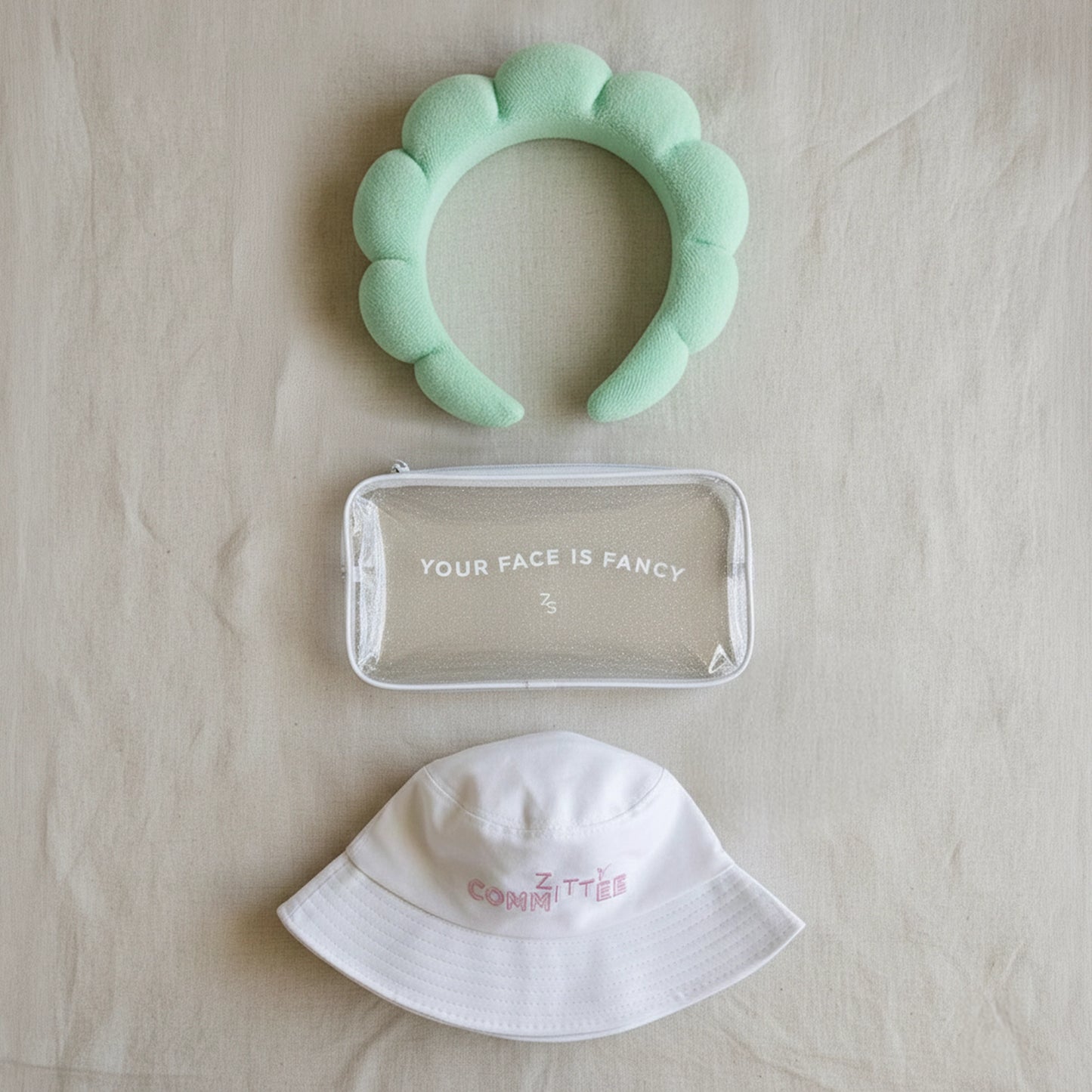 The #ZittyCommittee Kit features a mint headband, glitter make-up bag, and white bucket hat.