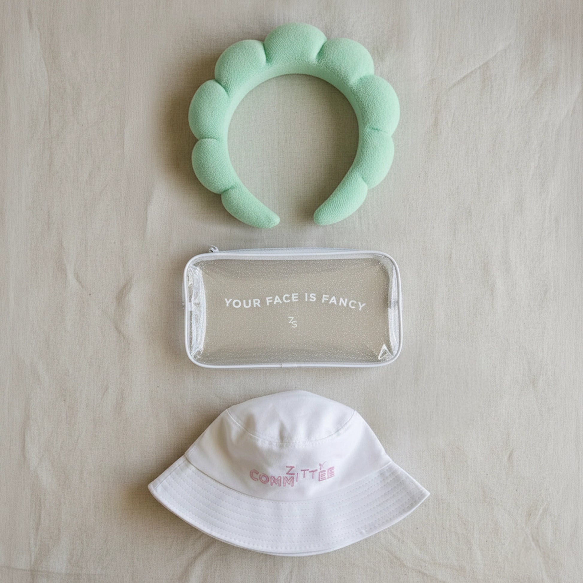 The #ZittyCommittee Kit features a mint headband, glitter make-up bag, and white bucket hat.